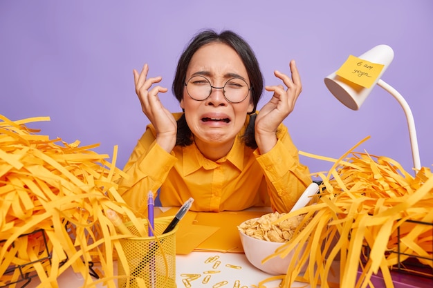 Una colegiala asiática deprimida miserable trabaja hasta tarde se prepara para el examen ¿la tarea en casa tiene muchas tareas que hacer?