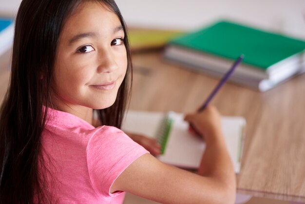 Colegiala asiática haciendo los deberes y mirando hacia atrás