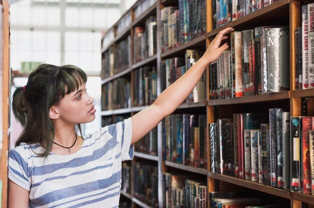 Colegiala buscando un libro en la biblioteca