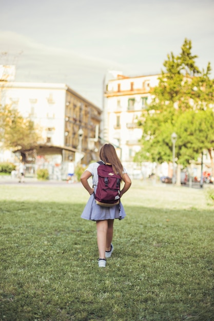 Colegiala caminando en el parque de la ciudad