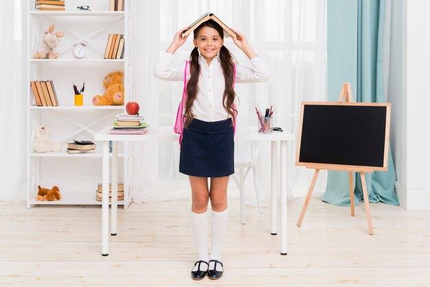 Colegiala étnica de pie bajo el techo del libro