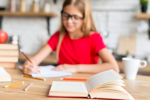 Foto gratuita colegiala haciendo tarea cerca de libros