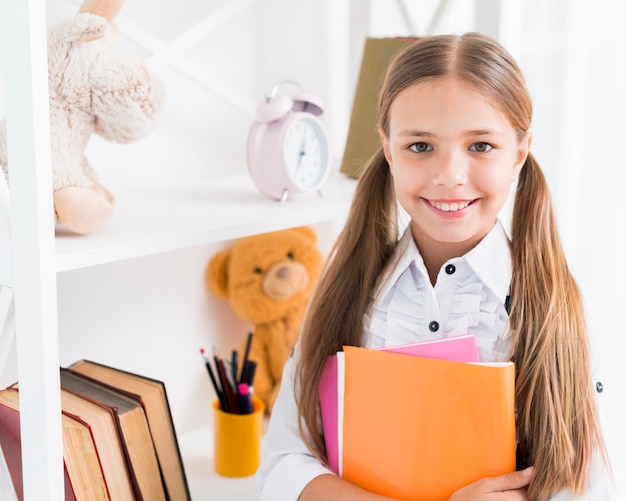 Colegiala inteligente de pie con cuadernos.