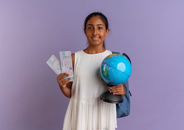 Colegiala joven complacida con bolsa trasera sosteniendo boletos y globo en púrpura