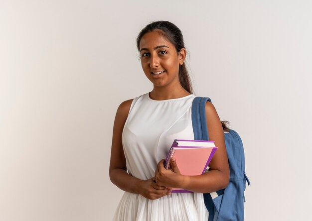 Colegiala joven complacido vistiendo bolsa trasera sosteniendo el portátil en blanco