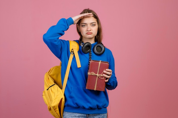 Colegiala de pie con la mano en la frente buscando