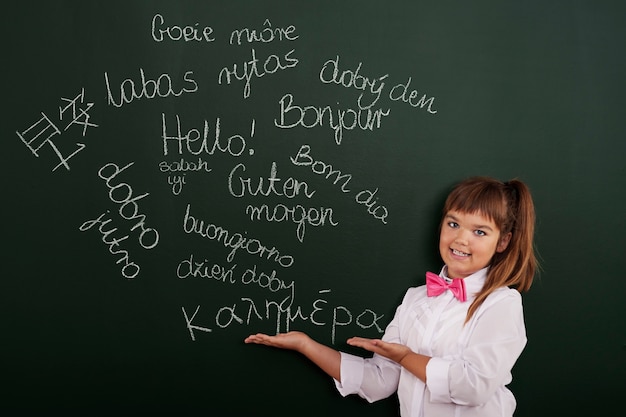 Foto gratuita colegiala presentando frases extranjeras en la pizarra