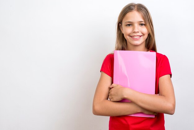 Colegiala sonriente llevando cuaderno