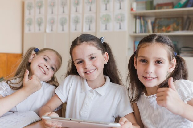 Colegialas con tableta gesticular pulgar arriba