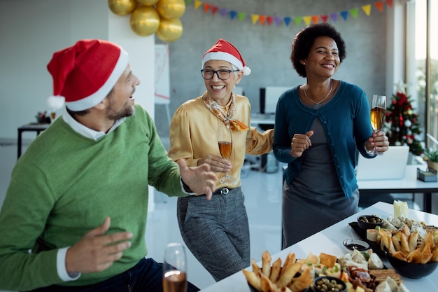 Colegios felices bailando y bebiendo champán mientras celebran el Año Nuevo en la fiesta de la oficina