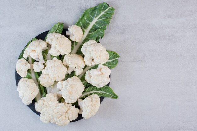 Coliflor fresca en rodajas con hojas en tablero negro. Foto de alta calidad