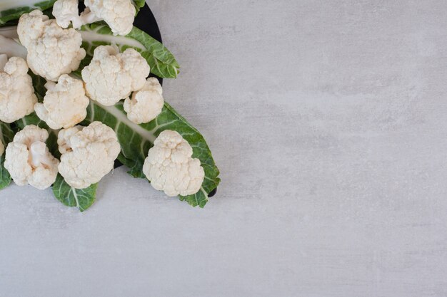 Coliflor fresca en rodajas con hojas en tablero negro. Foto de alta calidad