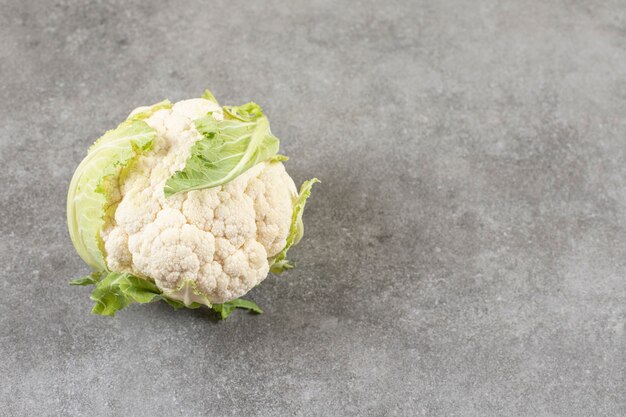 Coliflor madura fresca y repollo verde sobre mesa de piedra.