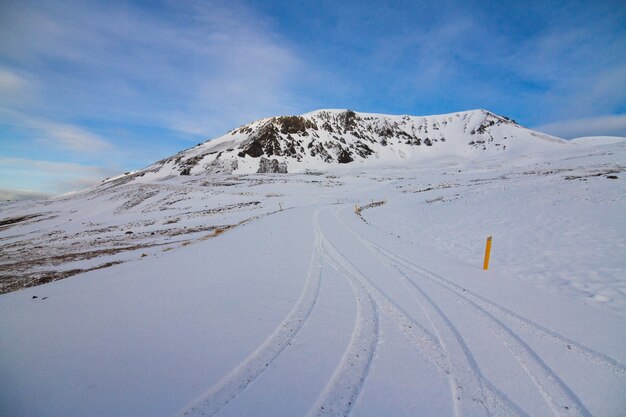 Colina cubierta de nieve bajo la luz del sol y un cielo azul durante el invierno en Islandia