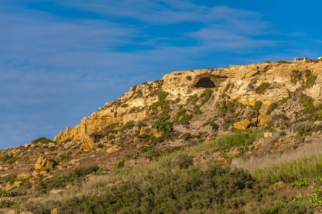 Colina rocosa con muchas plantas verdes bajo el hermoso cielo azul claro