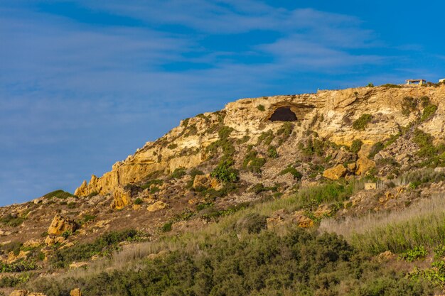 Colina rocosa con muchas plantas verdes bajo el hermoso cielo azul claro