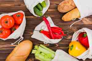 Foto gratuita colocación plana de bolsas reutilizables en superficie de madera con frutas y verduras.