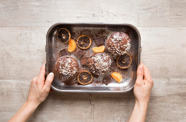 Colocación plana de donas en una bandeja de metal con cítricos secos