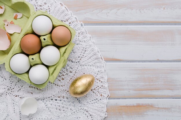 Colocación plana de huevos de pascua en cartón en tapete con espacio de copia