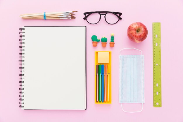 Colocación plana de materiales de regreso a la escuela con cuaderno y lápices.