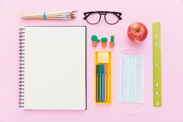 Colocación plana de materiales de regreso a la escuela con cuaderno y lápices.