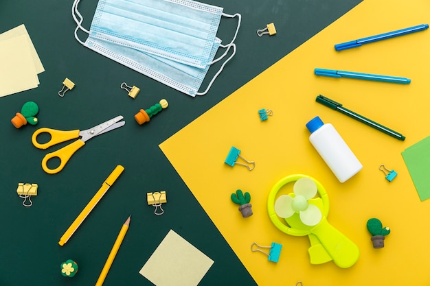 Colocación plana de materiales de regreso a la escuela con tijeras y mascarillas