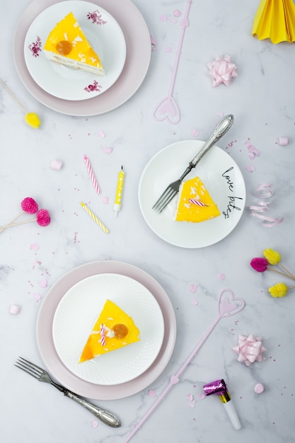Foto gratuita colocación plana de rebanadas de pastel en platos con decoraciones de cumpleaños
