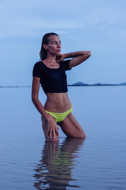 Colocar bronceada joven caucásica en el mar al atardecer