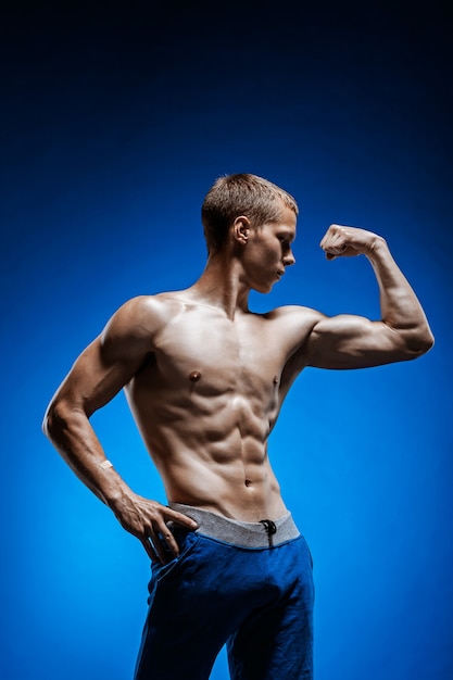 Colocar joven con hermoso torso en pared azul