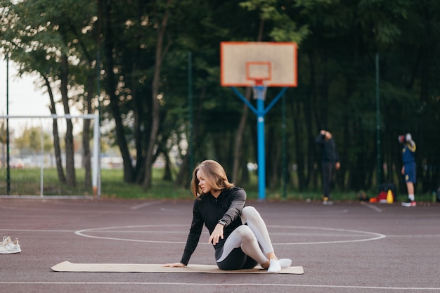 Colocar joven mujer en ropa deportiva entrena al aire libre en el patio de recreo.