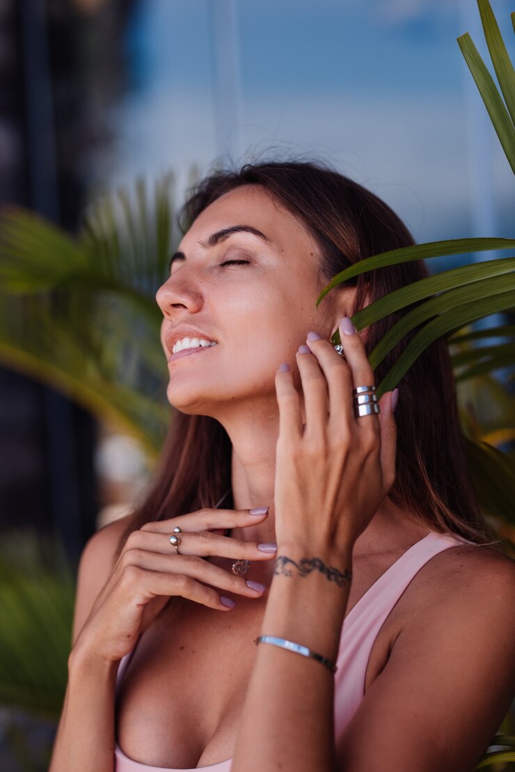 Colocar mujer caucásica bronceada en bikini con anillos, hojas tropicales alrededor