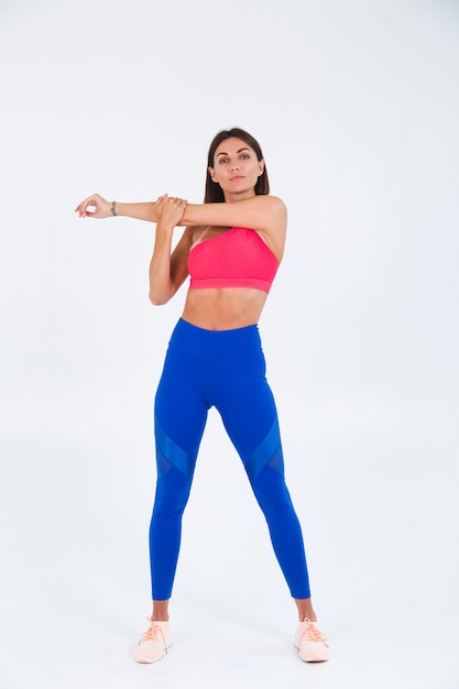 Colocar mujer deportiva bronceada con abdominales, curvas de fitness, vistiendo top y leggings azules sobre blanco