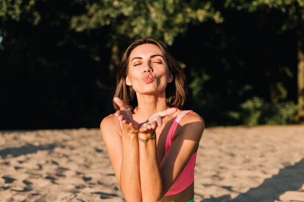 Colocar mujer deportiva en perfecta forma al atardecer en la playa en pose de yoga tranquila