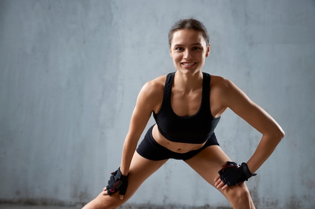 Colocar sonriente mujer practicando estiramiento de piernas