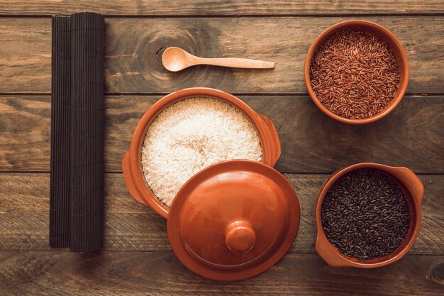 Coloque la estera con arroz crudo en diferentes tazones en la mesa de madera