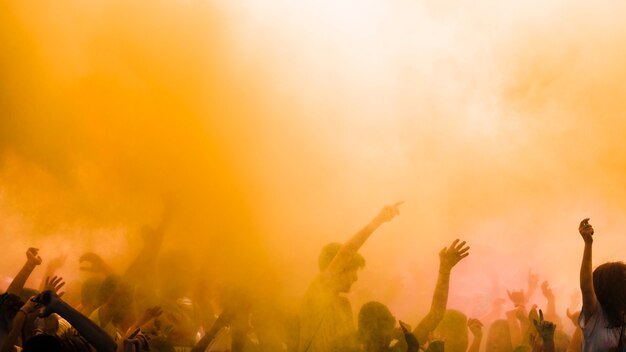 Color amarillo explota sobre la multitud disfrutando del festival holi.