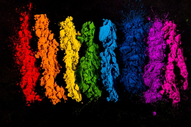Colores en polvo de colores dispuestos en fila sobre fondo negro