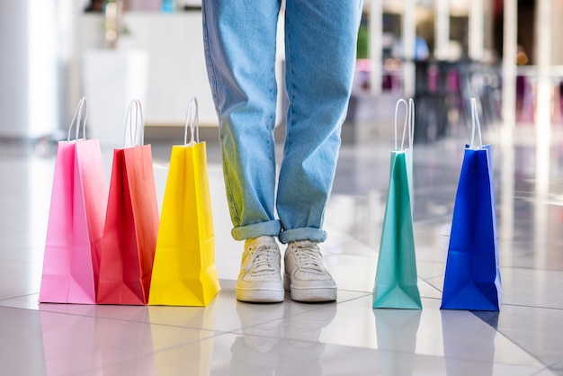 Coloridas bolsas de compras cerca de las piernas