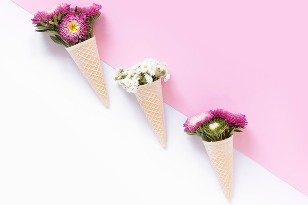 Foto gratuita coloridas flores en cono de helado de galleta sobre fondo dual