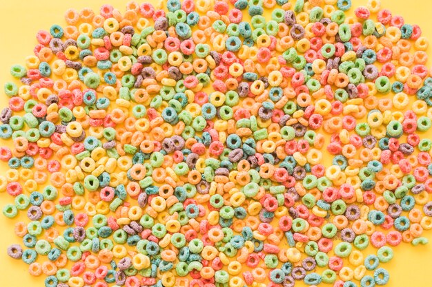 Coloridos anillos de lazo de cereal sobre fondo amarillo