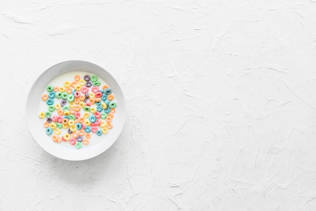 Foto gratuita coloridos cereales flotando en un tazón de leche sobre textura rugosa