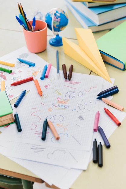 Coloridos crayones de cera esparcidos en el escritorio con dibujos infantiles.