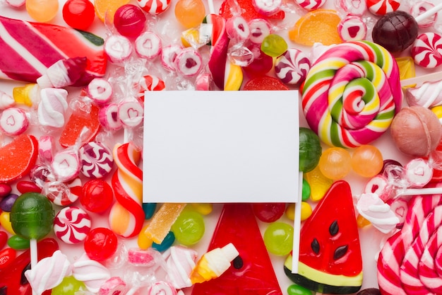 Foto gratuita coloridos y deliciosos dulces con tarjeta en blanco