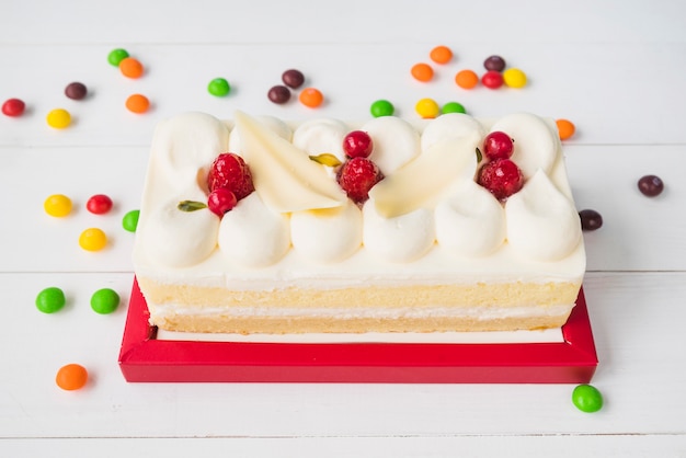 Foto gratuita coloridos dulces alrededor de la torta en la mesa de madera