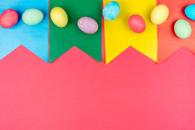 Coloridos huevos de Pascua en banderas de papel en mesa roja