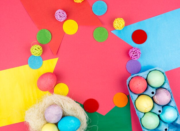 Coloridos huevos de Pascua en caja y en nido sobre mesa