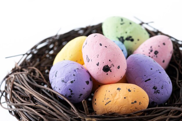 Coloridos huevos de Pascua dentro de un nido aislado sobre fondo blanco.