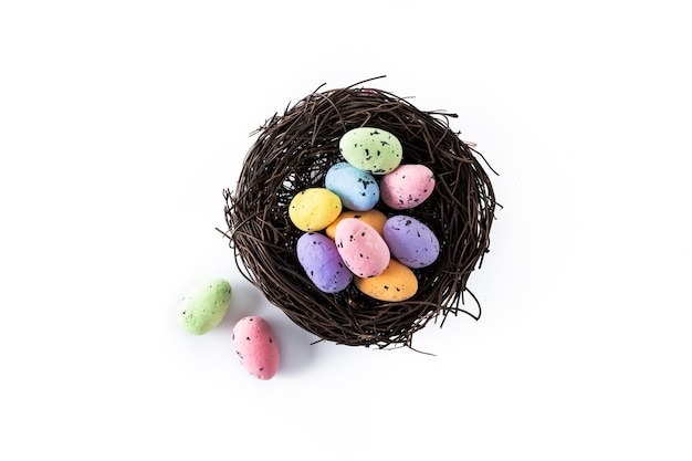 Coloridos huevos de Pascua dentro de un nido aislado sobre fondo blanco.