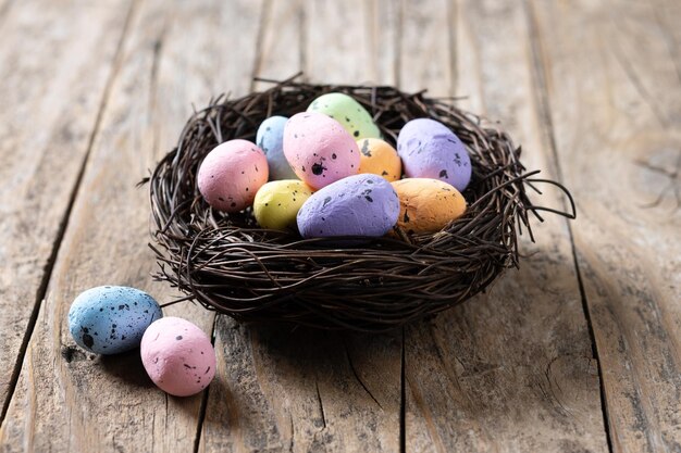 Coloridos huevos de Pascua dentro de un nido en una mesa de madera