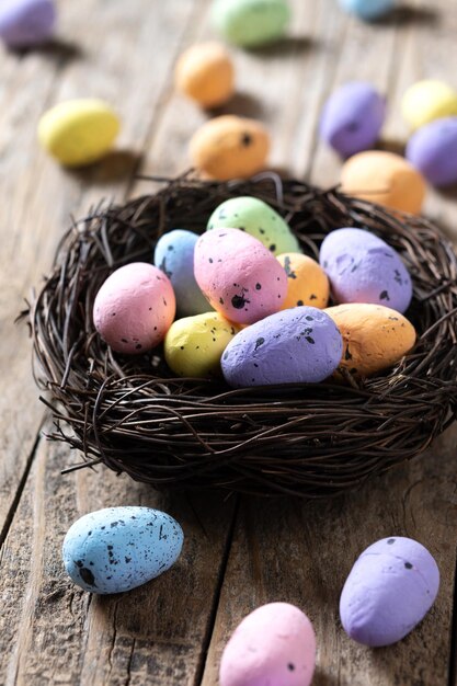 Coloridos huevos de Pascua dentro de un nido en una mesa de madera